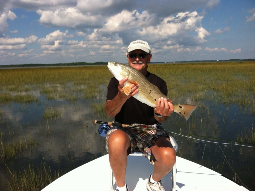 Inshore - angler holding redfish with fly rod in lap