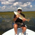 Inshore - angler holding redfish with fly rod in lap